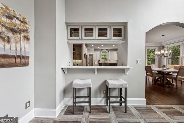 115 Hopewell Grove Dr, Milton, GA 30004 - kitchen featuring glass insert cabinets, a kitchen bar, a chandelier, arched walkways, and baseboards