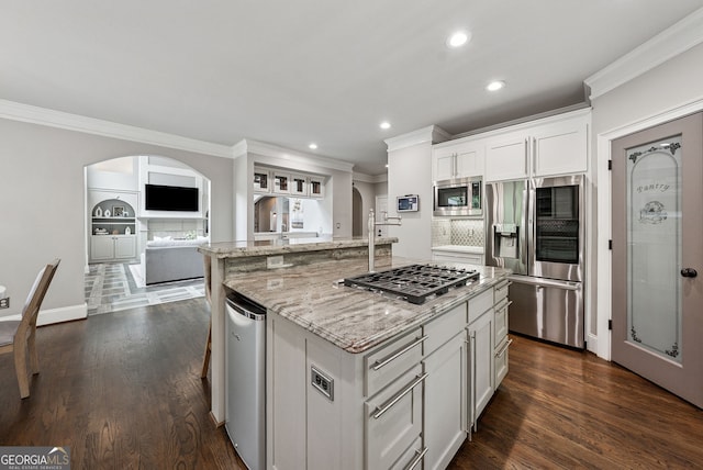 115 Hopewell Grove Dr, Milton, GA 30004 - kitchen with stainless steel appliances, arched walkways, ornamental molding, an island with sink, and light stone countertops