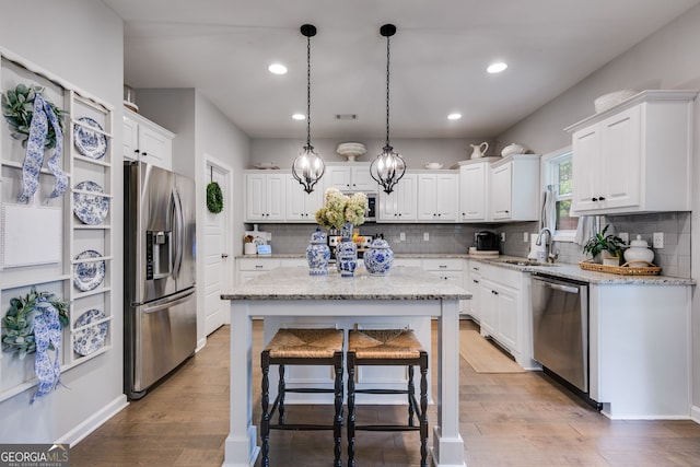 13 Westbrook Rd, Carrollton, GA 30116 - kitchen with appliances with stainless steel finishes, light wood-style flooring, white cabinetry, a kitchen island, and recessed lighting