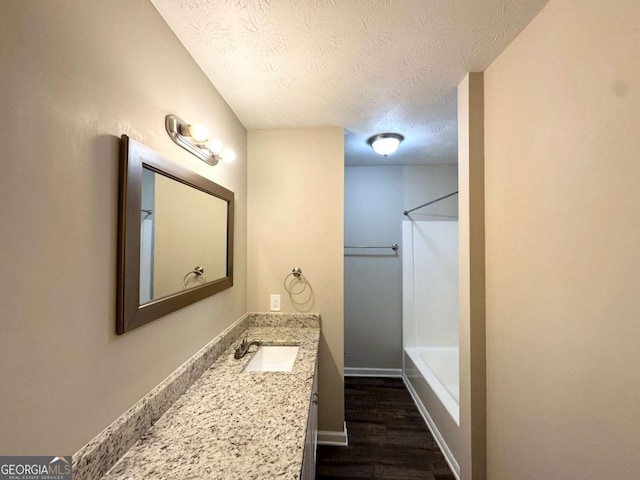 1918 Leigh Dr SW, Conyers, GA 30094 - bathroom with a textured ceiling, vanity, wood finished floors, shower / washtub combination, and baseboards