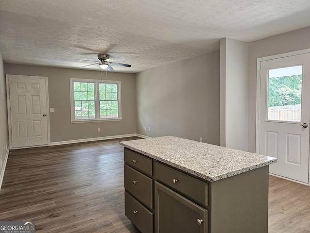70 Shadow Ln, Carrollton, GA 30117 - kitchen with ceiling fan, a textured ceiling, dark wood-type flooring, a center island, and baseboards