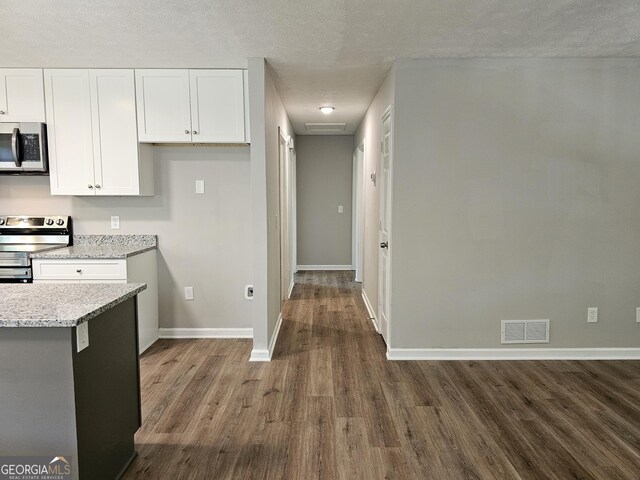 70 Shadow Ln, Carrollton, GA 30117 - kitchen with stainless steel appliances, dark wood finished floors, white cabinets, baseboards, and light stone countertops