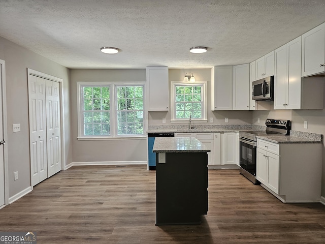 70 Shadow Ln, Carrollton, GA 30117 - kitchen featuring appliances with stainless steel finishes, dark wood-style flooring, stone countertops, a kitchen island, and white cabinetry