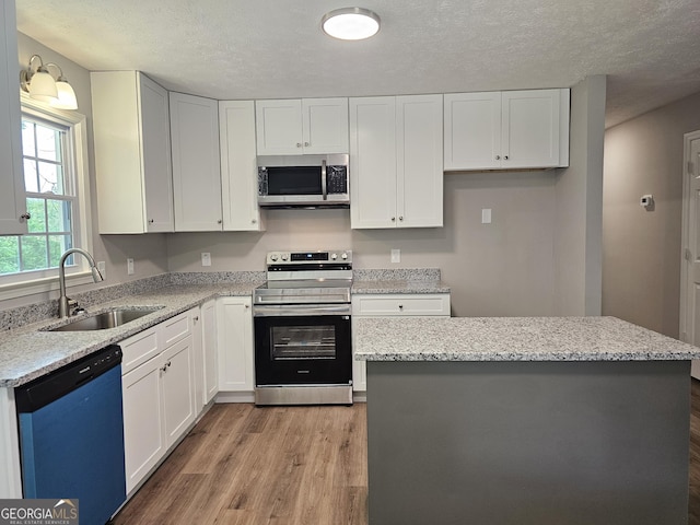 70 Shadow Ln, Carrollton, GA 30117 - kitchen with appliances with stainless steel finishes, a sink, light wood-type flooring, white cabinets, and a textured ceiling