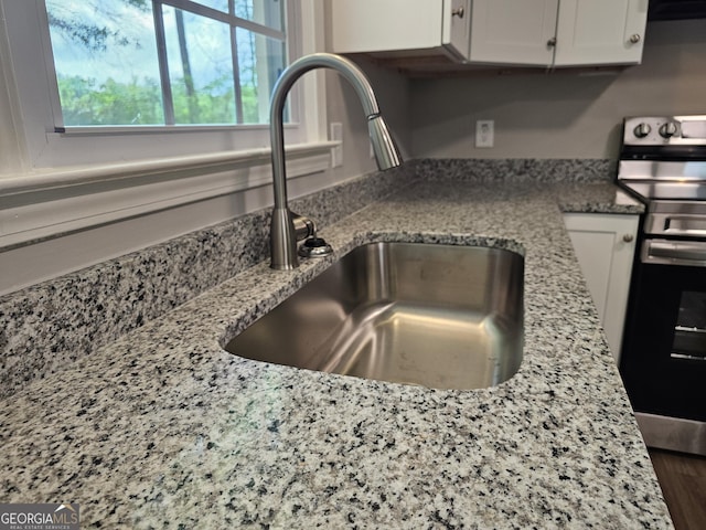 70 Shadow Ln, Carrollton, GA 30117 - kitchen view of electric range, a sink, white cabinetry, light stone counters, and range hood
