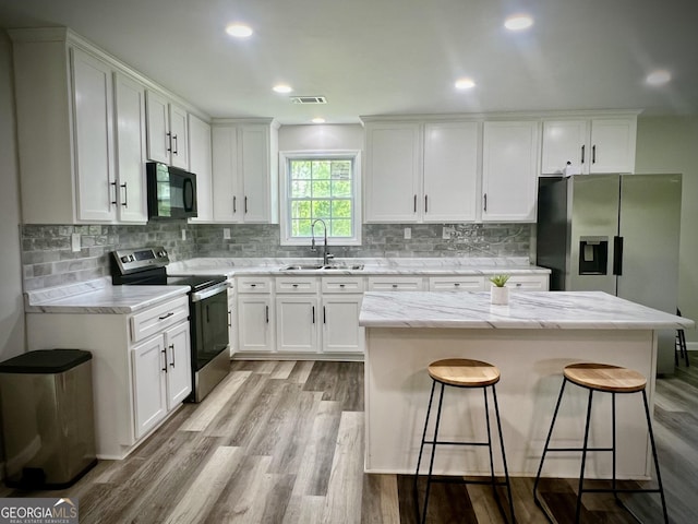 1962 Anderson Rd, Rentz, GA 31075 - kitchen featuring stainless steel appliances, a sink, white cabinetry, light wood-style flooring, and light stone countertops