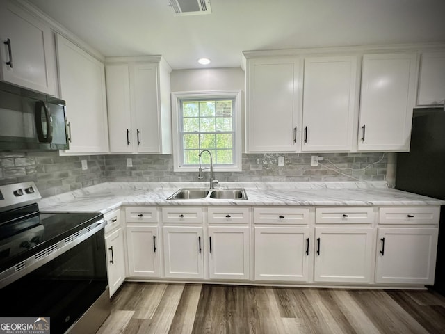 1962 Anderson Rd, Rentz, GA 31075 - kitchen featuring stainless steel electric range oven, black microwave, a sink, white cabinets, and decorative backsplash