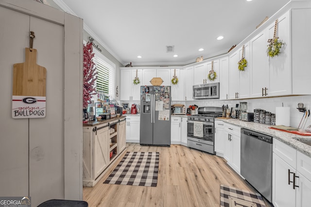 49 Grove Ct, Royston, GA 30662 - kitchen with stainless steel appliances, ornamental molding, tasteful backsplash, light wood-style flooring, and white cabinets