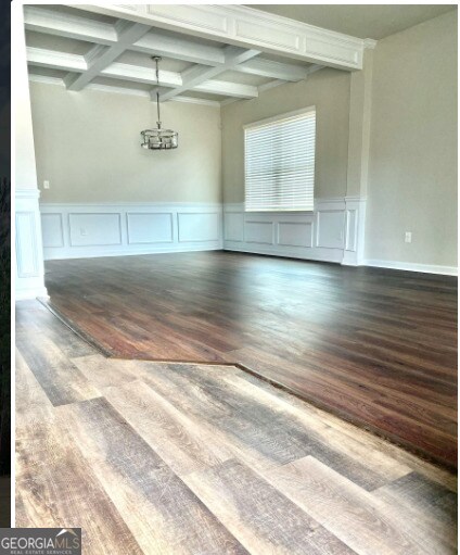 413 Atlas Ct, Locust Grove, GA 30248 - unfurnished room with coffered ceiling, wood finished floors, beam ceiling, a decorative wall, and a wainscoted wall