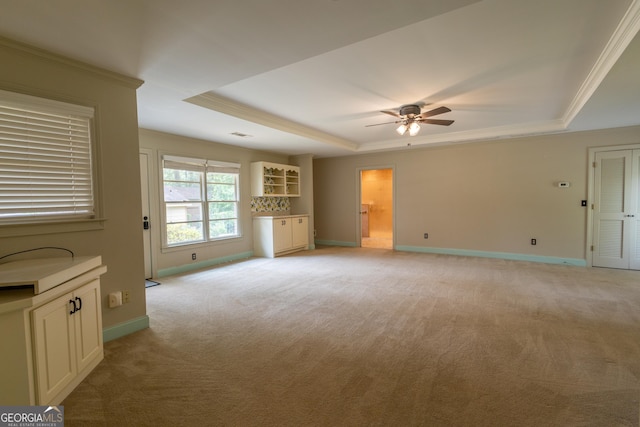 6214 Crestview Dr SE, Covington, GA 30014 - unfurnished living room featuring a tray ceiling, light carpet, a ceiling fan, baseboards, and crown molding