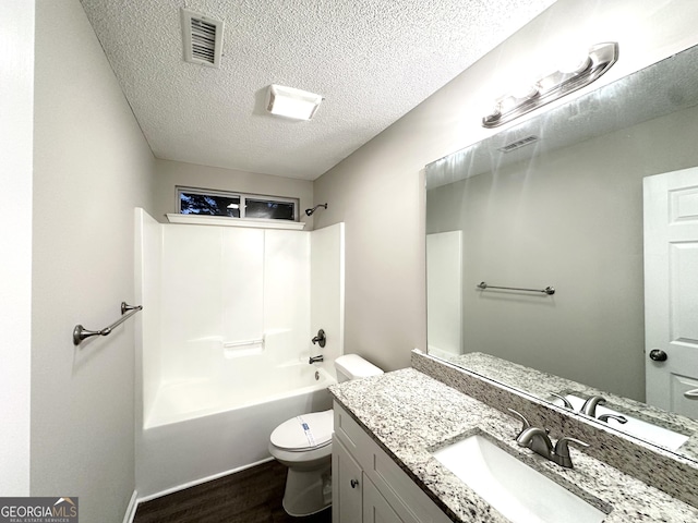 408 Kendall Ln, Mcdonough, GA 30253 - bathroom featuring toilet, wood finished floors, vanity, a textured ceiling, and tub / shower combination