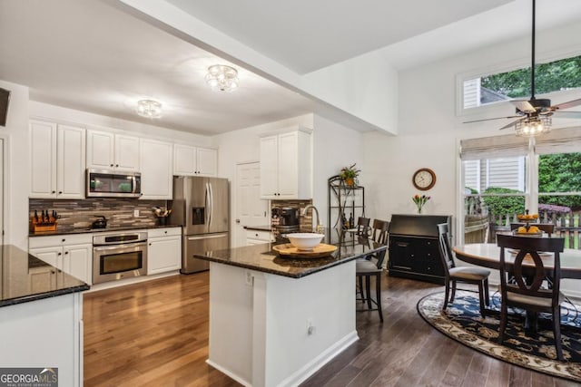 107 W Point Trl, Woodstock, GA 30189 - kitchen with appliances with stainless steel finishes, white cabinetry, dark wood finished floors, and decorative backsplash