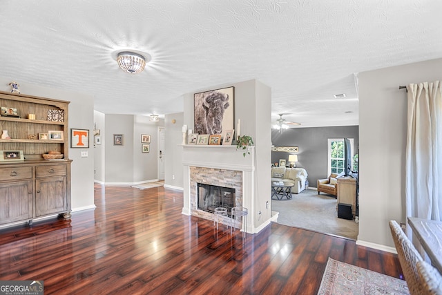 81 Maple Creek Dr, Newnan, GA 30263 - living area featuring wood finished floors, a stone fireplace, baseboards, a ceiling fan, and a textured ceiling