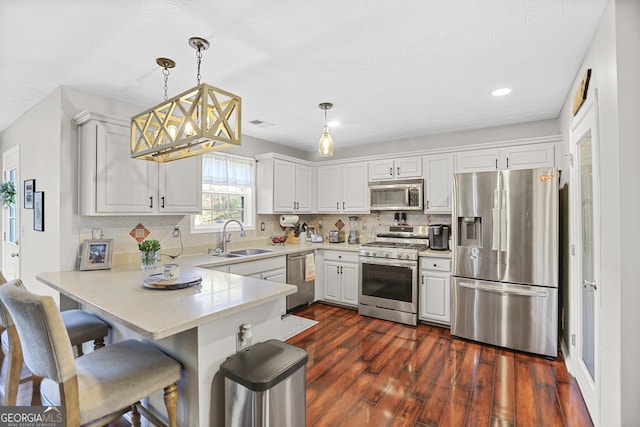 81 Maple Creek Dr, Newnan, GA 30263 - kitchen with appliances with stainless steel finishes, a sink, a peninsula, dark wood-type flooring, and tasteful backsplash