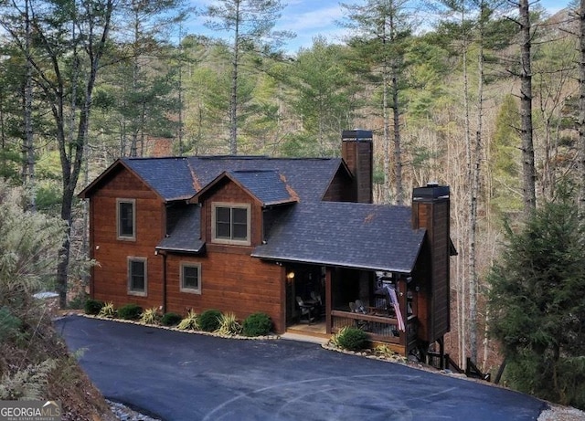1061 Fir Ln, Ellijay, GA 30540 - view of front of house with a chimney, a porch, a shingled roof, a view of trees, and asphalt driveway