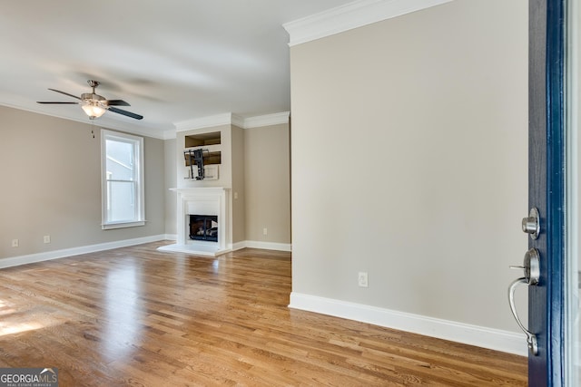 3641 Ridge Towne Dr, Duluth, GA 30096 - unfurnished living room featuring ornamental molding, ceiling fan, light wood-style flooring, and a glass covered fireplace