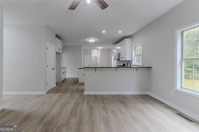 1706 Brandon Lee Way, Marietta, GA 30008 - kitchen with a peninsula, white cabinetry, ceiling fan, light wood-style flooring, and a breakfast bar area