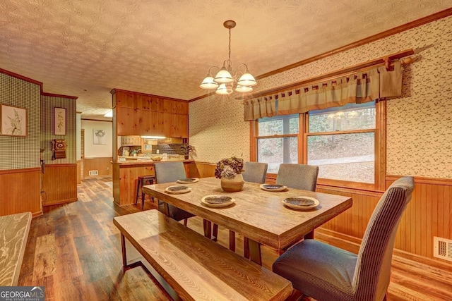 3452 Monica Ln SW, Conyers, GA 30094 - dining area featuring wallpapered walls, a wainscoted wall, wood finished floors, a chandelier, and a textured ceiling