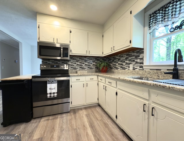 253 Yonah Valley Rd, Cleveland, GA 30528 - kitchen featuring appliances with stainless steel finishes, white cabinets, a sink, tasteful backsplash, and light wood-style floors