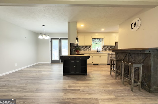 253 Yonah Valley Rd, Cleveland, GA 30528 - kitchen with stainless steel dishwasher, a sink, white cabinets, light wood finished floors, and backsplash