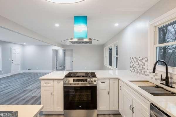 1506 Vine St NE, Gainesville, GA 30501 - kitchen featuring appliances with stainless steel finishes, island exhaust hood, a sink, open floor plan, and light countertops