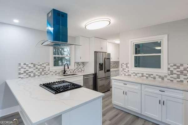 1506 Vine St NE, Gainesville, GA 30501 - kitchen with appliances with stainless steel finishes, island range hood, a peninsula, a sink, and light wood finished floors