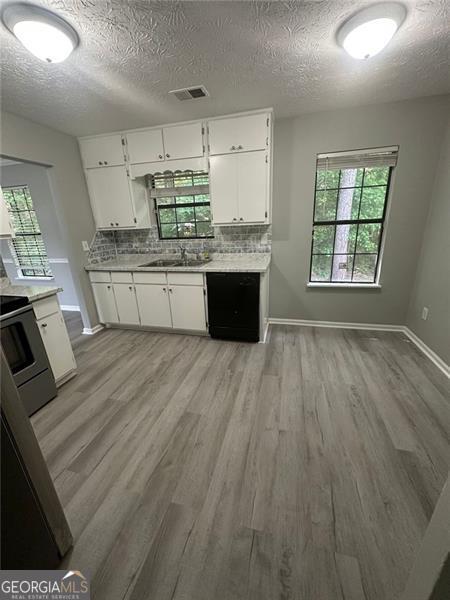 5388 Robertson Path, Lithonia, GA 30038 - kitchen featuring range, light wood-style floors, a textured ceiling, light countertops, and a sink