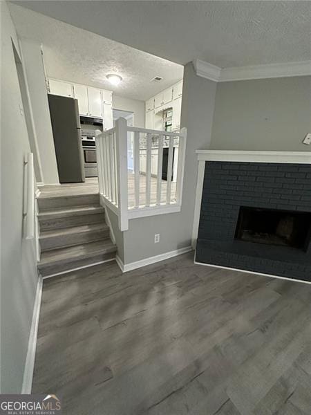5388 Robertson Path, Lithonia, GA 30038 - unfurnished living room featuring a textured ceiling, baseboards, crown molding, a brick fireplace, and dark wood-type flooring