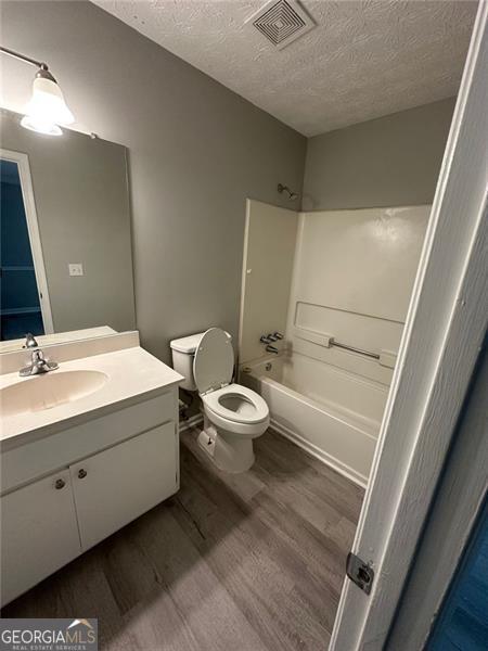 5388 Robertson Path, Lithonia, GA 30038 - full bathroom featuring toilet, a textured ceiling, vanity, wood finished floors, and shower / bathtub combination