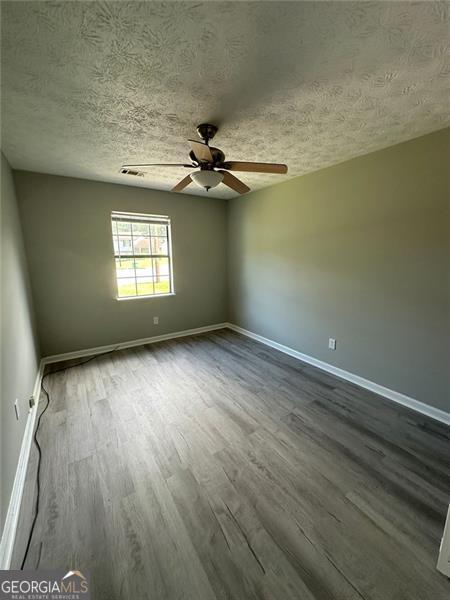 5388 Robertson Path, Lithonia, GA 30038 - unfurnished room with dark wood-type flooring, baseboards, ceiling fan, and a textured ceiling