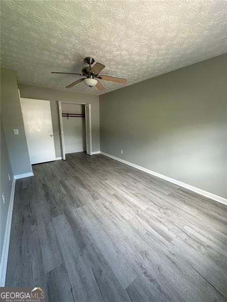 5388 Robertson Path, Lithonia, GA 30038 - unfurnished bedroom featuring dark wood-style floors, baseboards, a closet, a textured ceiling, and a ceiling fan
