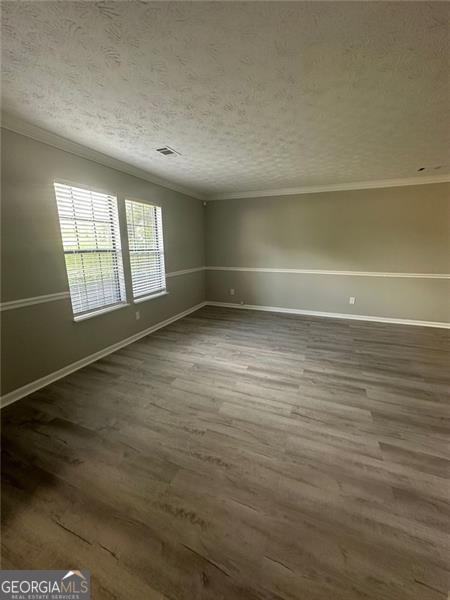 5388 Robertson Path, Lithonia, GA 30038 - empty room with wood finished floors, ornamental molding, baseboards, a textured ceiling, and vaulted ceiling