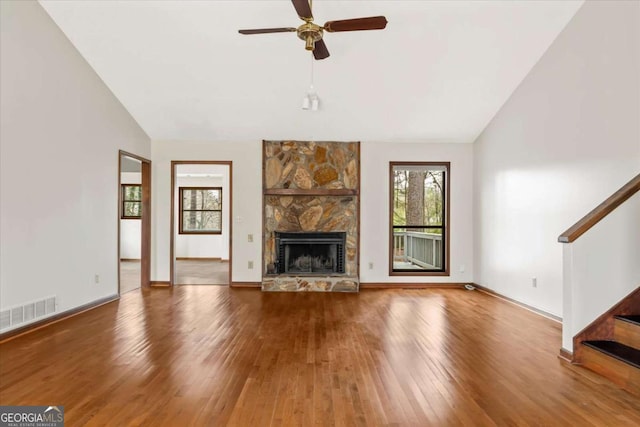3966 N Indian Cir NW, Kennesaw, GA 30144 - unfurnished living room featuring vaulted ceiling, wood finished floors, stairs, a stone fireplace, and ceiling fan