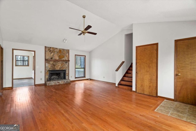 3966 N Indian Cir NW, Kennesaw, GA 30144 - unfurnished living room featuring a ceiling fan, wood finished floors, vaulted ceiling, stairs, and a stone fireplace