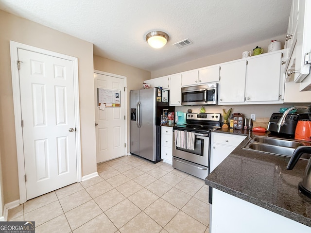 521 Lake Jordan Blvd W, Kingsland, GA 31548 - kitchen with stainless steel appliances, dark countertops, white cabinets, light tile patterned floors, and a textured ceiling