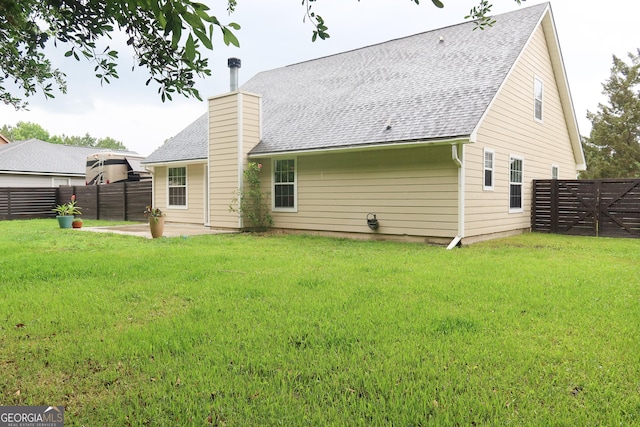 521 Lake Jordan Blvd W, Kingsland, GA 31548 - back of property with a fenced backyard, a patio area, roof with shingles, and a chimney