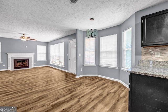 2505 Tiffany Ct, Conyers, GA 30013 - unfurnished living room with wood finished floors, ceiling fan, baseboards, a fireplace with flush hearth, and a chandelier