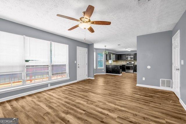2505 Tiffany Ct, Conyers, GA 30013 - unfurnished living room featuring a textured ceiling, dark wood finished floors, baseboards, and a ceiling fan