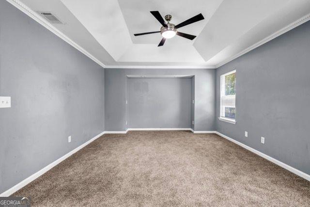 2505 Tiffany Ct, Conyers, GA 30013 - carpeted empty room featuring a tray ceiling, ceiling fan, ornamental molding, and baseboards