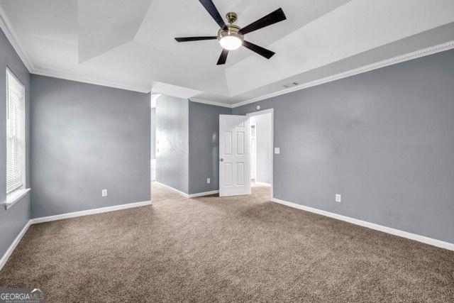 2505 Tiffany Ct, Conyers, GA 30013 - empty room featuring carpet floors, a ceiling fan, a raised ceiling, crown molding, and baseboards