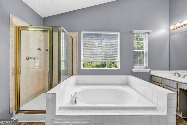 2505 Tiffany Ct, Conyers, GA 30013 - bathroom featuring vanity, a bath, a stall shower, and vaulted ceiling