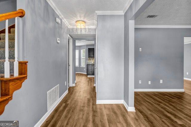 2505 Tiffany Ct, Conyers, GA 30013 - corridor with stairway, wood finished floors, baseboards, crown molding, and a textured ceiling