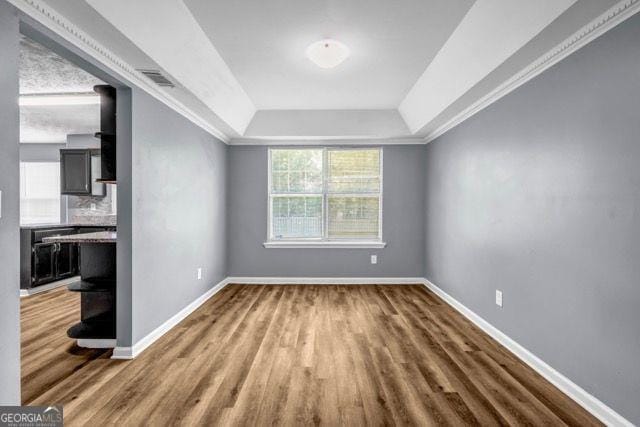 2505 Tiffany Ct, Conyers, GA 30013 - unfurnished living room featuring a tray ceiling, wood finished floors, baseboards, and crown molding