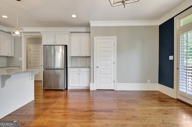 46 Horseshoe Bend Way, Senoia, GA 30276 - kitchen featuring freestanding refrigerator, ornamental molding, white cabinets, decorative backsplash, and a kitchen breakfast bar