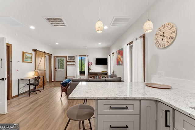 457 Monroe Ridge Rd, Sautee Nacoochee, GA 30571 - kitchen featuring a barn door, light wood-type flooring, gray cabinetry, light stone countertops, and open floor plan