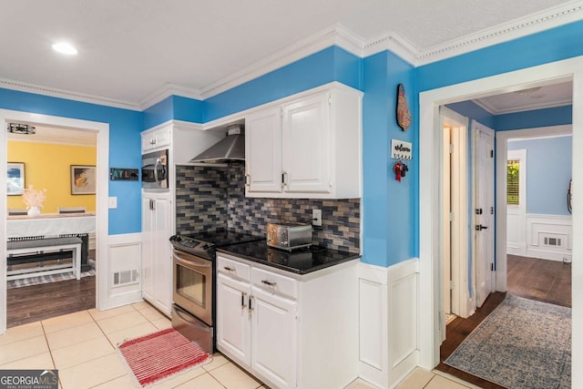 4259 Kings Troop Rd, Stone Mountain, GA 30083 - kitchen featuring stainless steel appliances, wall chimney exhaust hood, white cabinetry, dark countertops, and wainscoting
