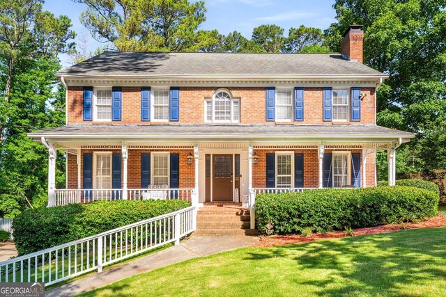 4259 Kings Troop Rd, Stone Mountain, GA 30083 - colonial house featuring covered porch, a chimney, and brick siding
