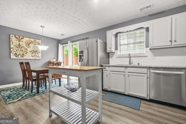 2959 Pritchards Mill Trl, Douglasville, GA 30135 - kitchen featuring stainless steel appliances, a sink, light wood finished floors, a textured ceiling, and backsplash