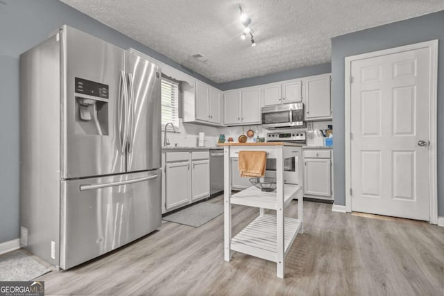 2959 Pritchards Mill Trl, Douglasville, GA 30135 - kitchen featuring stainless steel appliances, a textured ceiling, light wood-style floors, light countertops, and baseboards