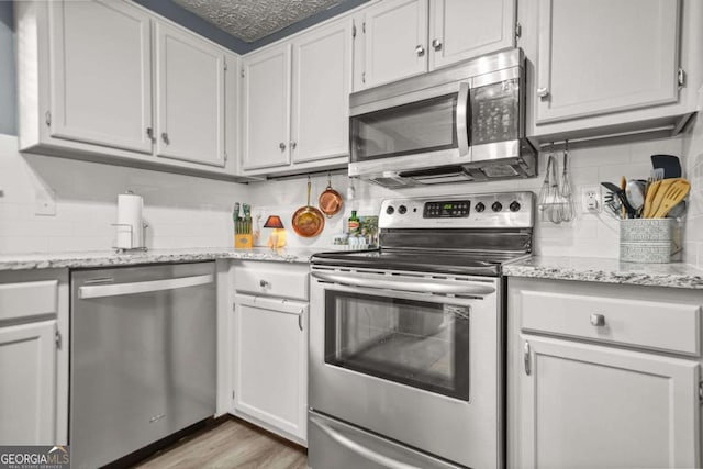 2959 Pritchards Mill Trl, Douglasville, GA 30135 - kitchen featuring appliances with stainless steel finishes, decorative backsplash, light wood-type flooring, and light stone countertops